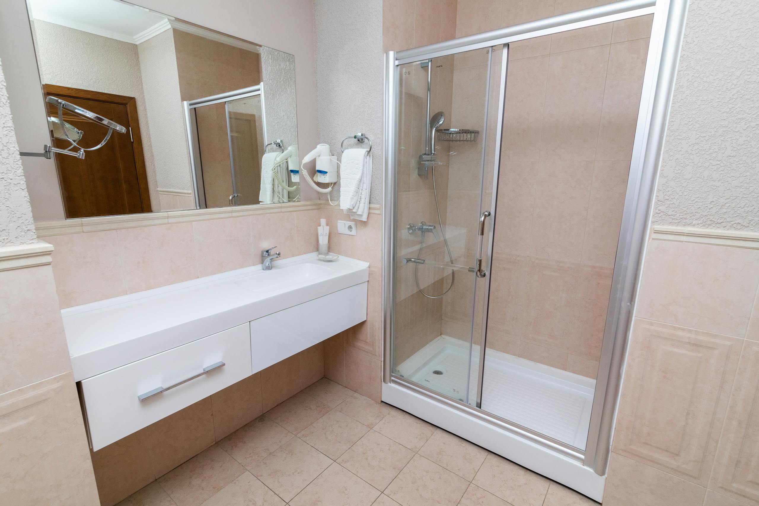 Contemporary bathroom equipped with a shower stall, large mirror, and a minimalist white vanity